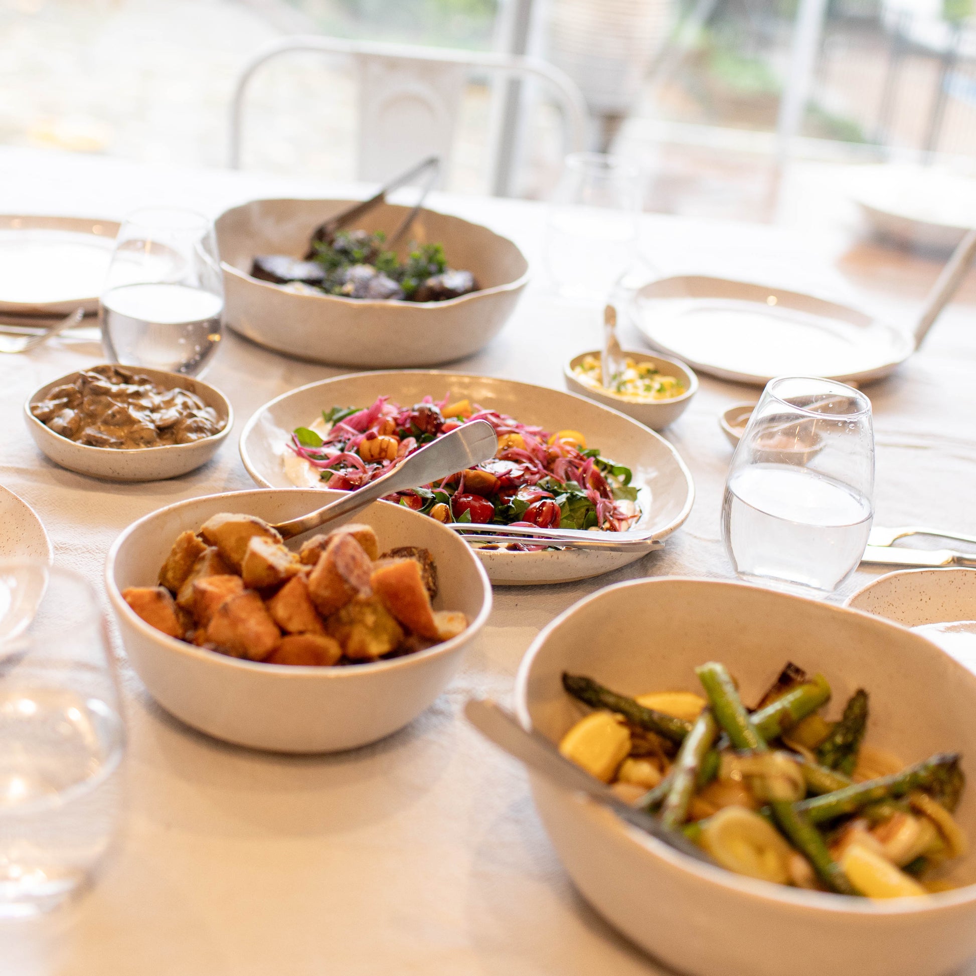 Table with various dishes of food on a blurred outdoor background