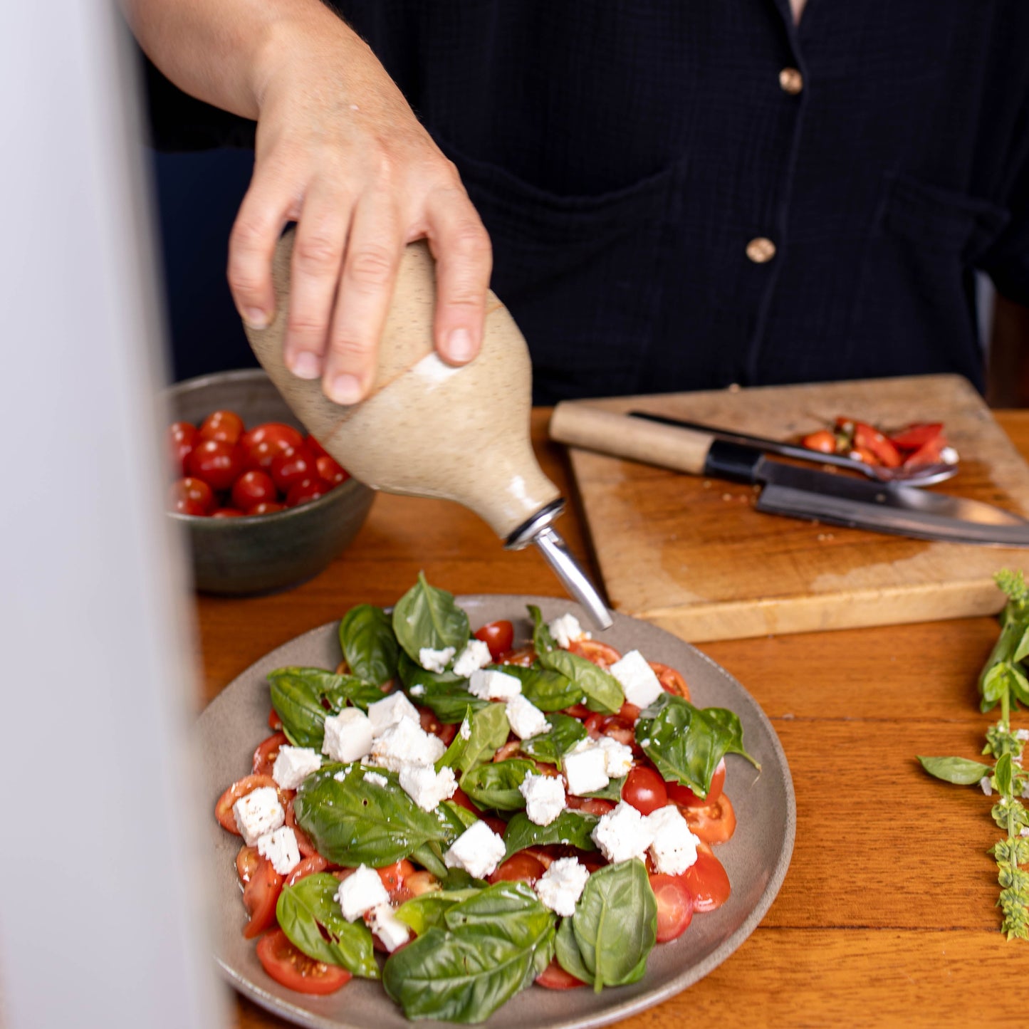 Woman pouring dressing from a Lil Ceramics handmade oil pourer onto a salad on a wooden table