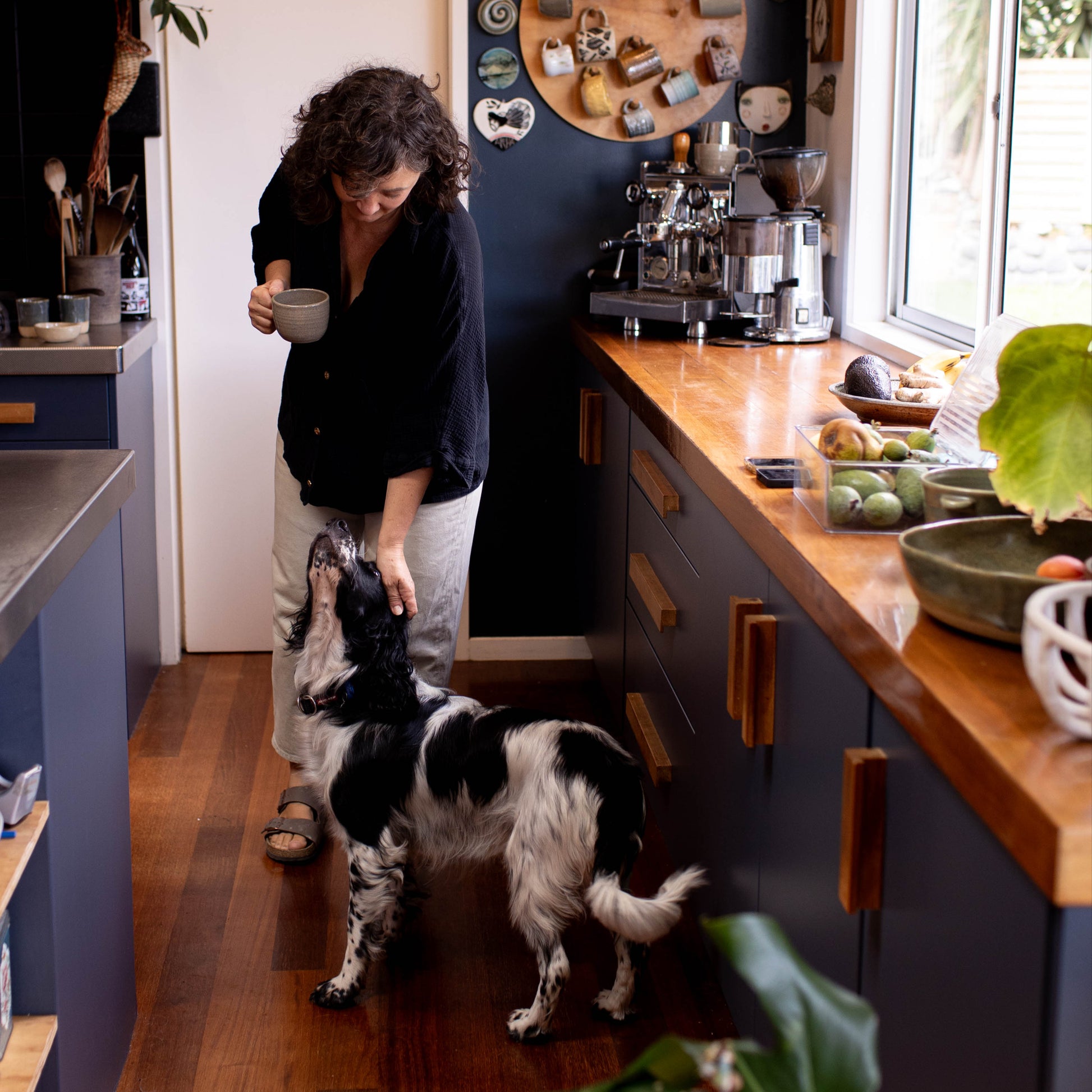 Person in a kitchen with a dog, surrounded by various kitchen items and decor.