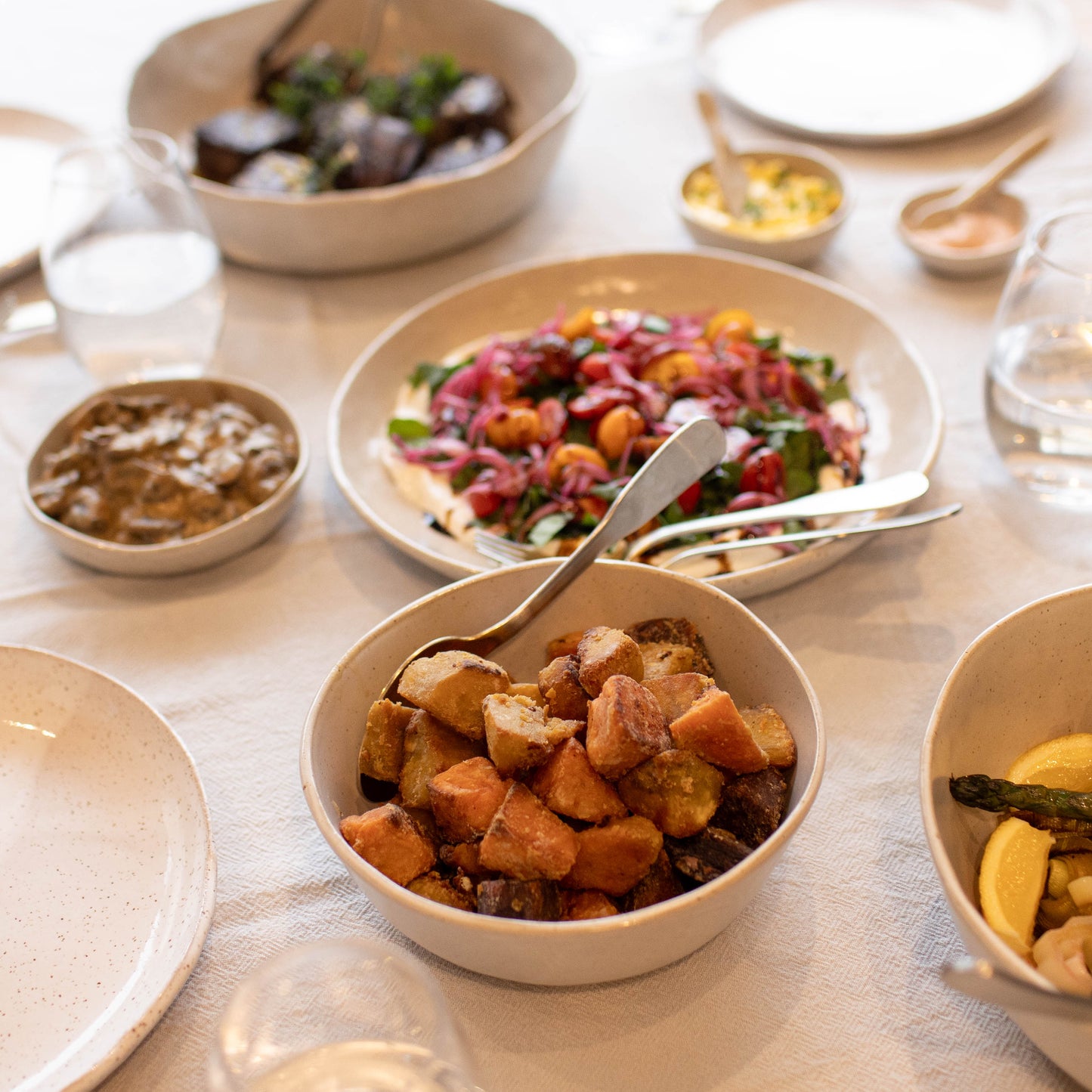 Table with various dishes of food including bowls and plates.