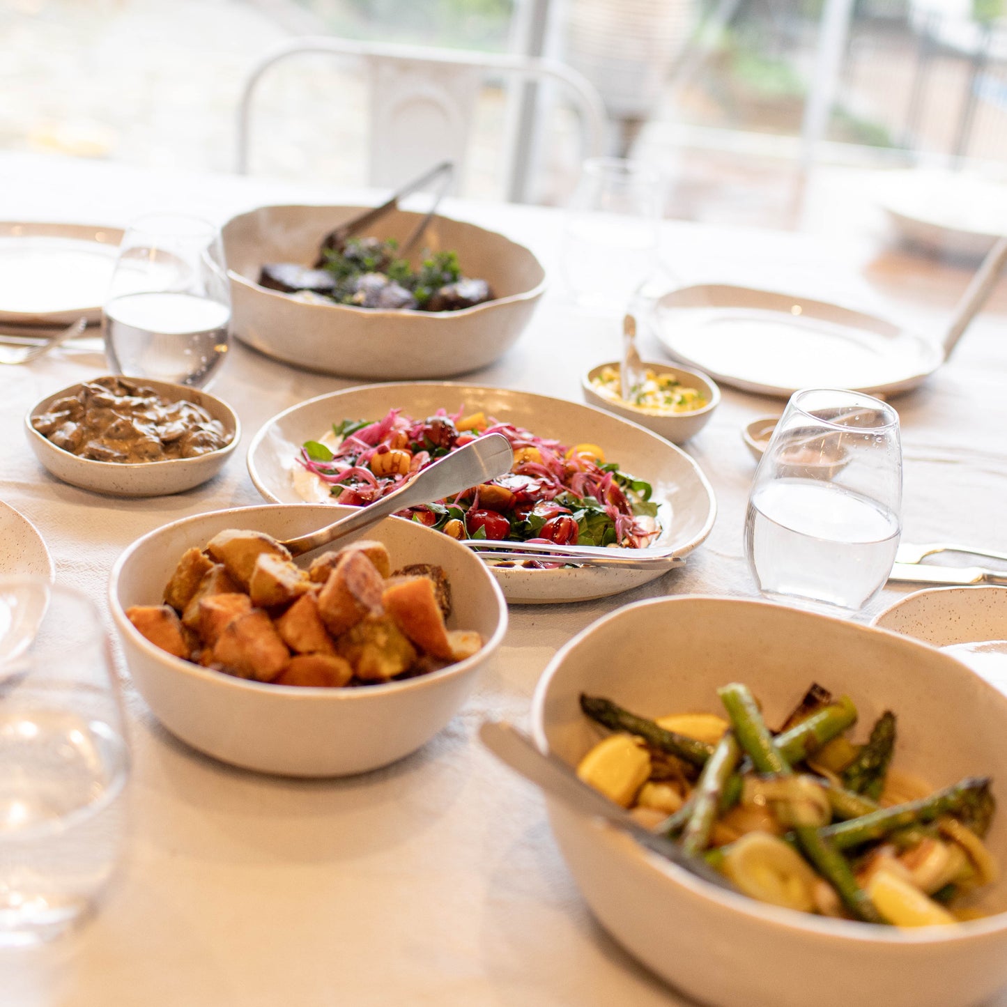Table with various dishes of food on a blurred outdoor background